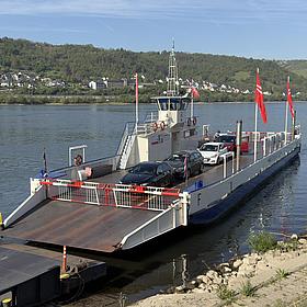 Am Anleger liegt eine Autofähre und Autos werden entladen. 