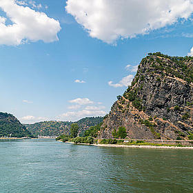 Ein großer Felsen mit Bewuchs ist von Wasser umgeben.