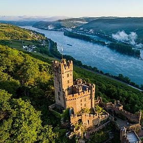 Die Burg Sooneck ragt über die Weinberge hinaus, im Hintergrund der Rhein in der Ferne