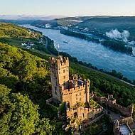 Die Burg Sooneck ragt über die Weinberge hinaus, im Hintergrund der Rhein in der Ferne