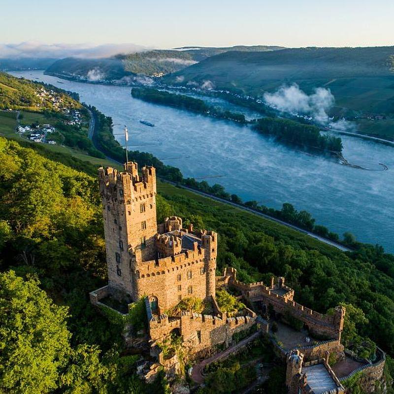 Die Burg Sooneck ragt über die Weinberge hinaus, im Hintergrund der Rhein in der Ferne