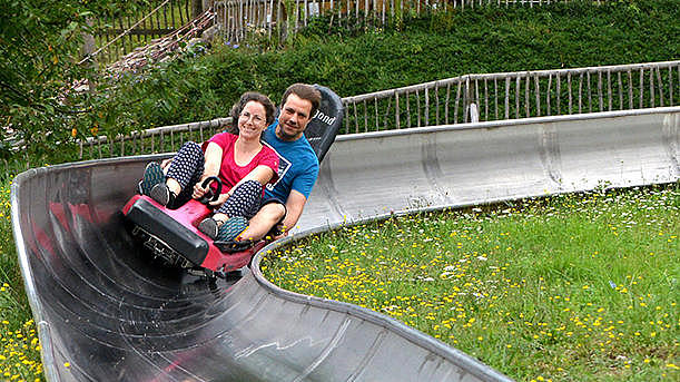 Two adults are riding on the toboggan run.