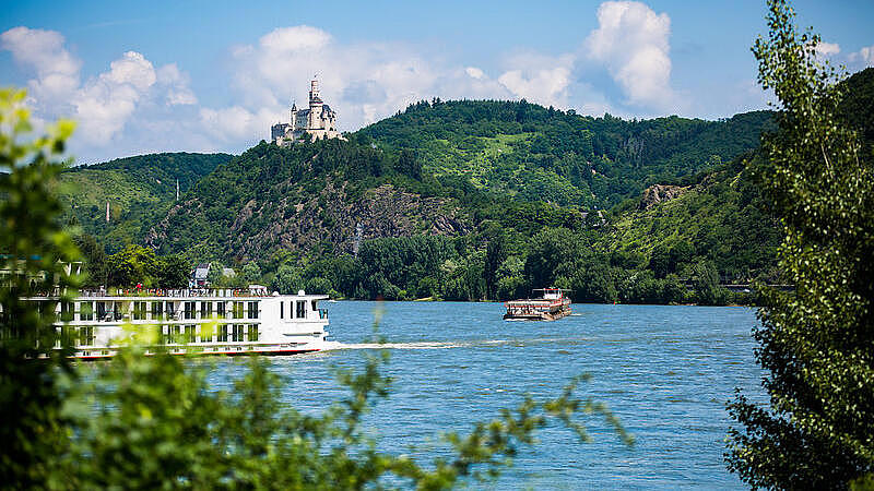 Two ships can be seen on the Rhine, with a castle on a hill in the background.