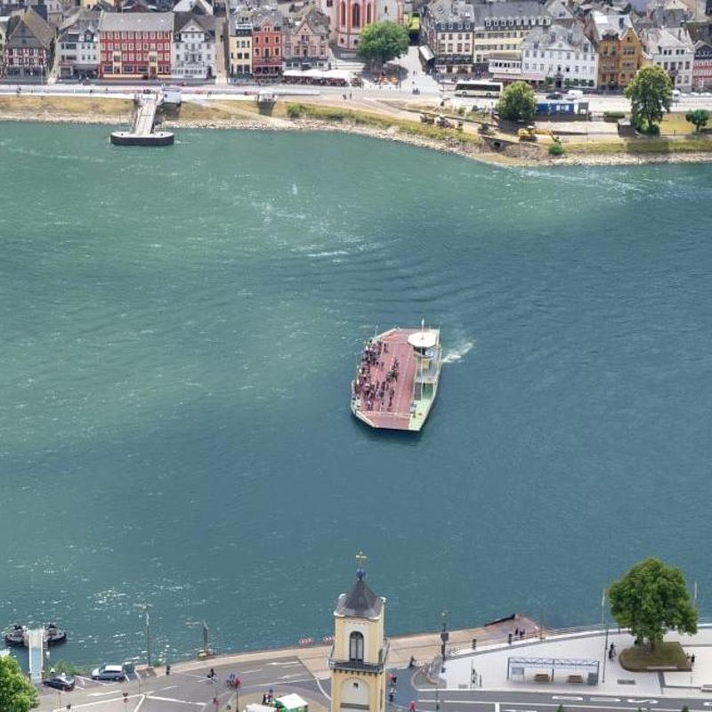 Two riverbanks, each with a small village, are visible. In the middle, a ferry is crossing the river.