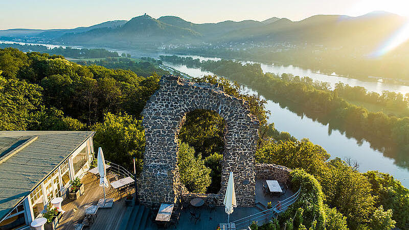 A bird's-eye view shows an old stone arch, with a river and hills in the background, all bathed in the sunset.